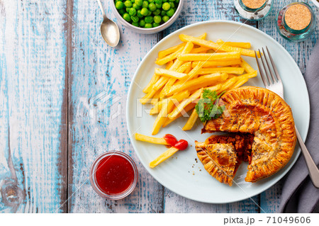Meat pie with french fries on a white plate. Wooden background. Copy space. Top view. Meat pie with french fries on a white plate. Wooden background. Copy space. Top view. 71049606