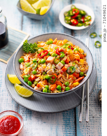 Asian fried rice with ham and vegetables. Blue wooden background. Close up. Asian fried rice with ham and vegetables. Blue wooden background. Close up. 71049621