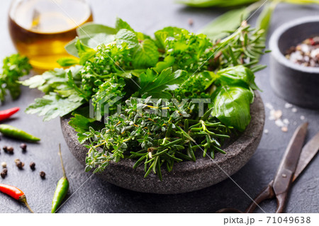 Fresh herbs in stone bowl with olive oil and spices. Grey background. Close up. 71049638