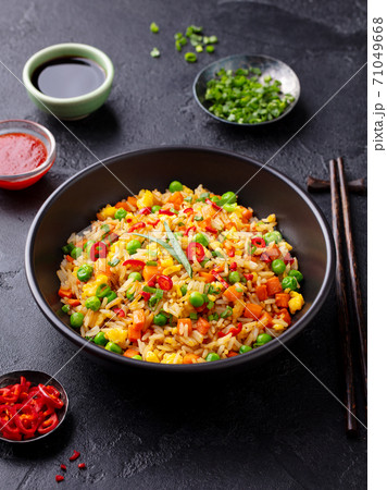 Asian fried rice with egg and vegetables. Dark stone background. Asian fried rice with egg and vegetables. Dark stone background. 71049668