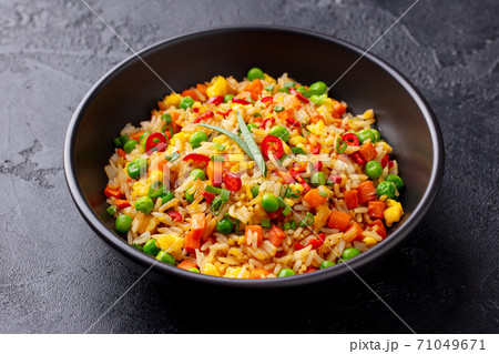 Asian fried rice with egg and vegetables. Dark stone background. Close up. Asian fried rice with egg and vegetables. Dark stone background. Close up. 71049671