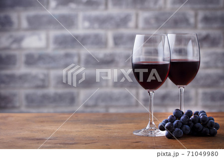 Glass of red wine and grape. Stone wall background. Wooden table. Close up. Glass of red wine and grape. Stone wall background. Wooden table. Close up. 71049980