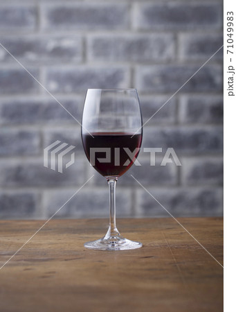 Glass of red wine on stone wall background. Wooden table. Close up. Glass of red wine on stone wall background. Wooden table. Close up. 71049983