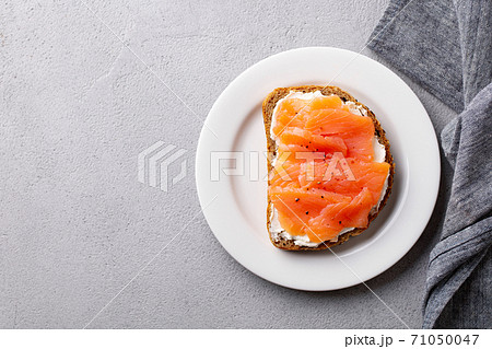 Sandwich, toast with smoked salmon and cream cheese on plate. Grey background. Copy space. Top view. 71050047
