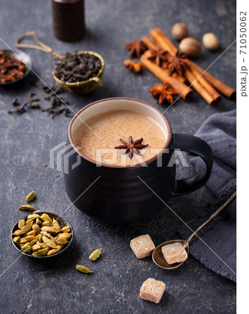 Indian masala tea with milk and spices in mug. Grey background. Close up. Indian masala tea with milk and spices in mug. Grey background. Close up. 71050062