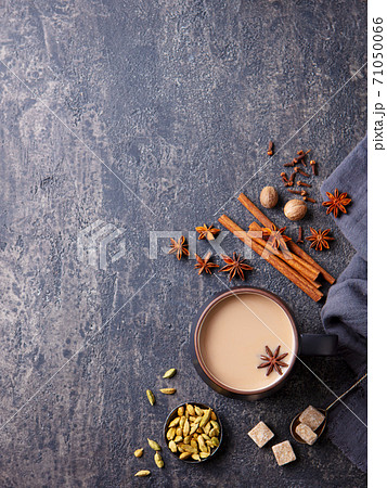 Indian masala tea with milk and spices in mug. Grey background. Copy space. Top view. Indian masala tea with milk and spices in mug. Grey background. Copy space. Top view. 71050066