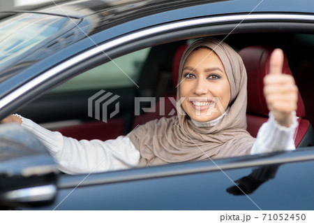 Positive muslim woman driving car, showing thumbs up Positive muslim woman driving car, showing thumbs up 71052450