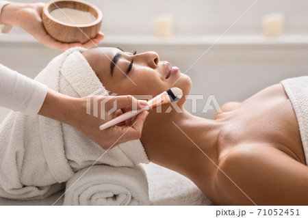 Beauty therapist applying face mask on young asian female skin at spa 71052451