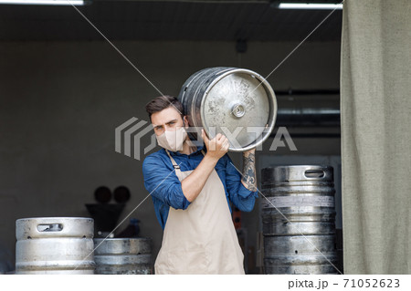 Young man working at warehouse in brewery or employee with keg Young man working at warehouse in brewery or employee with keg 71052623
