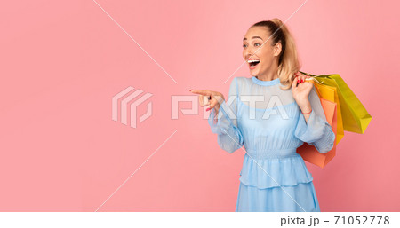Young woman with shopping bags pointing at free space 71052778