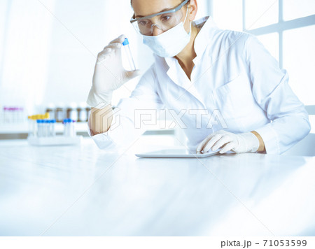 Female laboratory assistant analyzing a blood sample at hospital. Medicine, health care and researching concept Female laboratory assistant analyzing a blood sample at hospital. Medicine, health care and researching concept 71053599