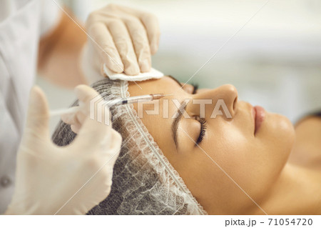 Cosmetologist making facial beauty injection to young woman in beauty salon 71054720