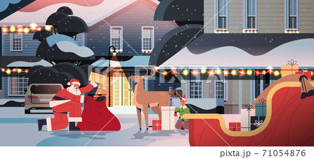 santa claus with deer and elf preparing gifts happy new year merry christmas holidays celebration concept 71054876