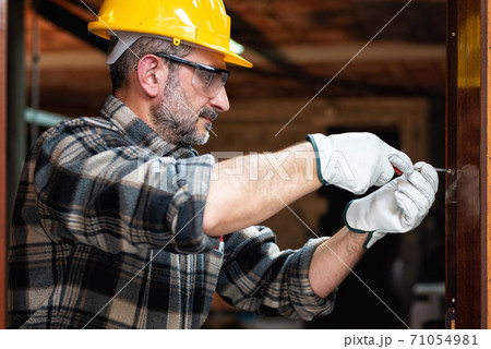 Carpenter at work repairs and installs the door frame of a room. Carpenter at work repairs and installs the door frame of a room. 71054981