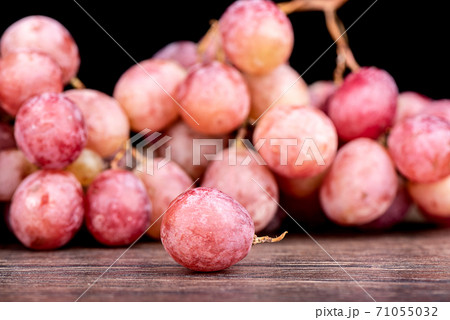 Selective focus. Grape berry and blurred bunch of red grapes. 71055032