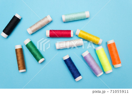 Colored sewing thread on a blue background 71055911