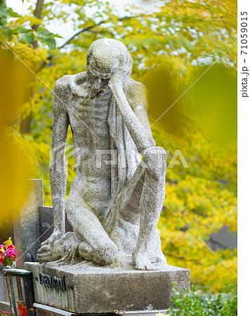 Skinny old man, male statue sitting on a tombstone. Skinny old man, male statue sitting on a tombstone. 71059015