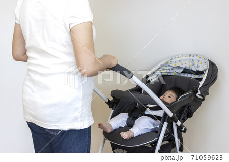 ベビーカーに乗る赤ちゃんと押す母親、生後4か月、女の子 71059623