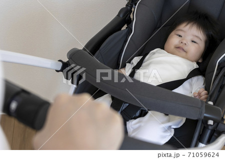 ベビーカーに乗る赤ちゃんと押す母親、生後4か月、女の子 ベビーカーに乗る赤ちゃんと押す母親、生後4か月、女の子 71059624