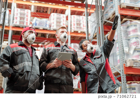 Young intercultural warehouse workers discussing new assortment at meeting Young intercultural warehouse workers discussing new assortment at meeting 71062721