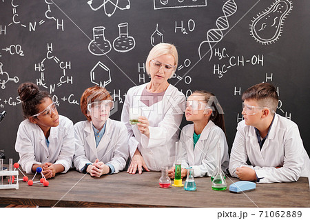 Young teacher of chemistry and group of pupils discussing chemical reaction Young teacher of chemistry and group of pupils discussing chemical reaction 71062889