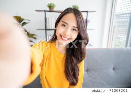 Pretty young asian female with big smile sitting at living room 71063201