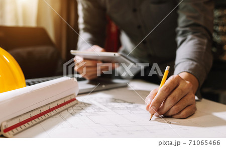 business man hand working and laptop with on on architectural project at construction site at office desk in office 71065466