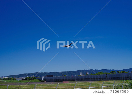 青空の広がる伊丹空港と着陸する小型旅客機のある風景 71067599