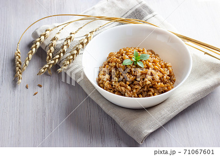 Spelt porridge in a bowl with basil. White wooden background. 71067601