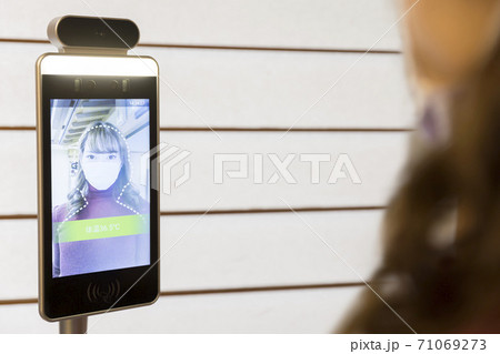非接触体温測定器を使って体温を測る若い女性 71069273