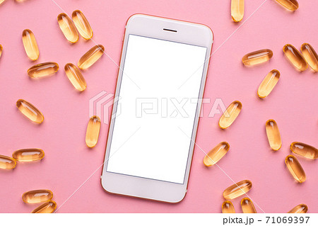 Mobile phone and Vitamins Omega 3 6 9 fish oil , vitamin D on a pink background for health lifestyle 71069397