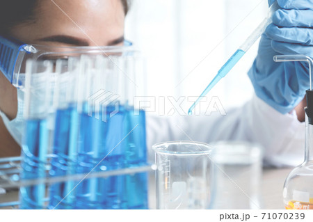 Scientists hand hold the pipette and drop the blue chemical liquid for research and analysis in a laboratory Scientists hand hold the pipette and drop the blue chemical liquid for research and analysis in a laboratory 71070239