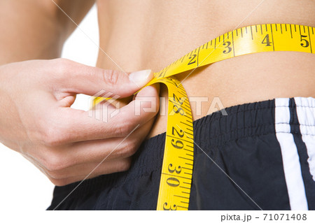 close up photo of a woman measuring her waist 71071408