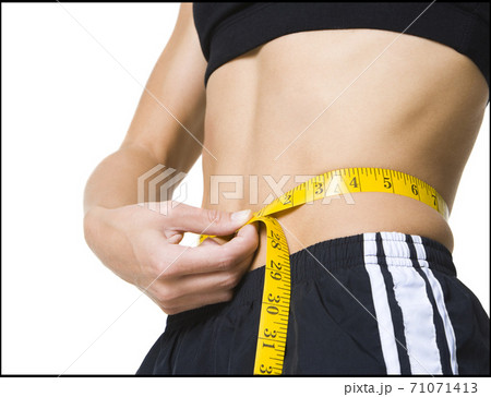 Close up of Young girl measuring waist Close up of Young girl measuring waist 71071413
