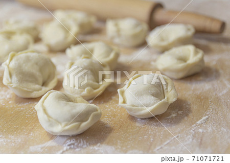 Closeup on semi-finished pelmeni dumplings on the wooden board. Closeup on semi-finished pelmeni dumplings on the wooden board. 71071721