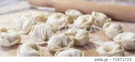 Closeup on semi-finished pelmeni dumplings on the wooden board. 71071723
