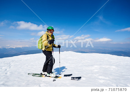 Sportsman skier on skis on snowy valley on background of bright blue sky and highland landscape. 71075870