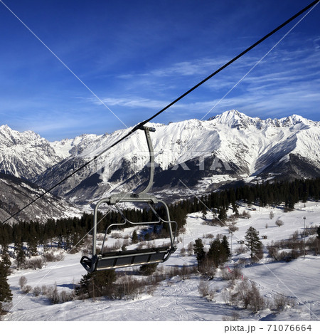 Chair-lift at ski resort and snowy winter mountains at nice sun day Chair-lift at ski resort and snowy winter mountains at nice sun day 71076664
