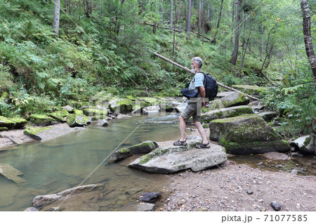 Man  standing on a stone near a mountain river  71077585