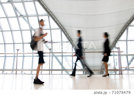 A people walking in motion blur on white corridor with large windows.  71078479