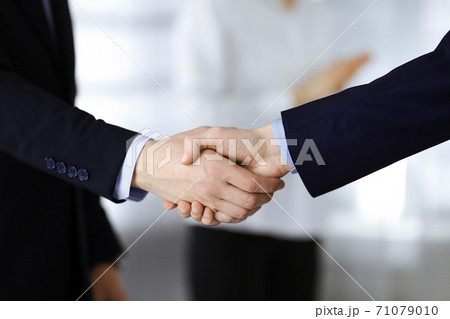 Business people shaking hands at meeting or negotiation, close-up. Group of unknown businessmen and a woman standing in a modern office. Teamwork, partnership and handshake concept Business people shaking hands at meeting or negotiation, close-up. Group of unknown businessmen and a woman standing in a modern office. Teamwork, partnership and handshake concept 71079010