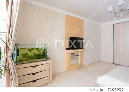 A fragment of the bedroom interior, a view of the wall opposite the bed, there is an aquarium against the wall and a TV hanging A fragment of the bedroom interior, a view of the wall opposite the bed, there is an aquarium against the wall and a TV hanging 71079394