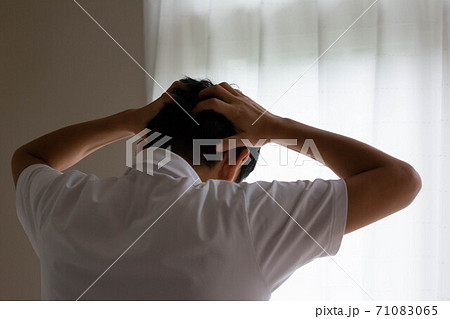 窓際で頭を抱える男性の後ろ姿 窓際で頭を抱える男性の後ろ姿 71083065
