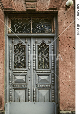 Blue double wooden door with carved details and openwork wrought iron bars on the Windows doors on the facade of a stone building Blue double wooden door with carved details and openwork wrought iron bars on the Windows doors on the facade of a stone building 71085469