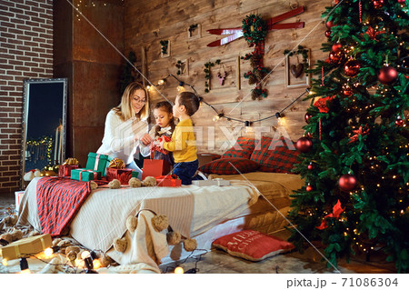 Mother and children with gifts in the house for Christmas 71086304