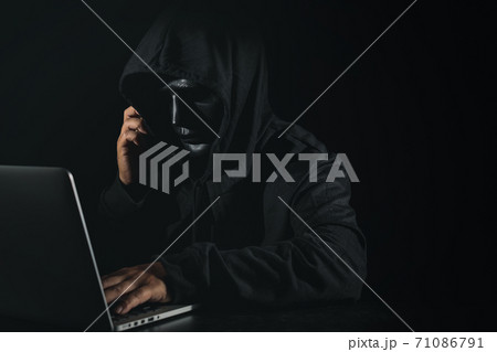 Dangerous anonymous hacker man in hooded and mask using computer and smartphone on black background, breaking into security data corporate server. Internet crime, cyber attack security concept Dangerous anonymous hacker man in hooded and mask using computer and smartphone on black background, breaking into security data corporate server. Internet crime, cyber attack security concept 71086791