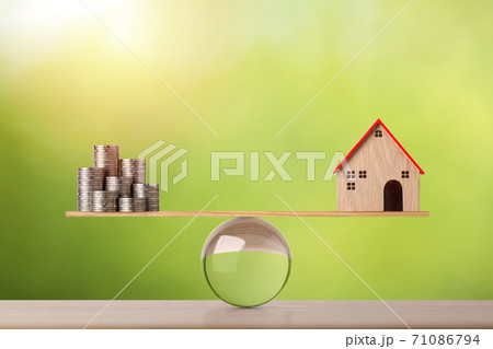 Model house on wooden marble seesaw balancing with stacking coins money on green background. Property investment and home mortgage financial real estate advertising concept Model house on wooden marble seesaw balancing with stacking coins money on green background. Property investment and home mortgage financial real estate advertising concept 71086794
