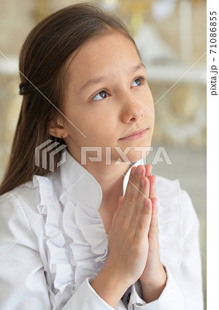 Close-up portrait of little girl in white blouse praying 71086855