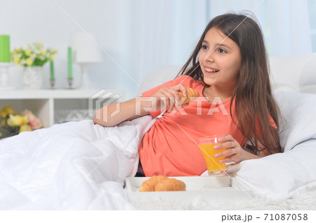 Cute girl with breakfast at home on bed 71087058
