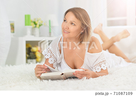 Portrait of young beautiful woman reading on bed Portrait of young beautiful woman reading on bed 71087109